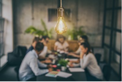 Young business people are discussing together a new startup project. A glowing light bulb as a new idea.