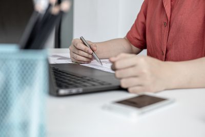A corporate finance employee is pointing at the document with a pen to verify the accuracy of the financial documents that have been prepared for the meeting with management. Financial concept.