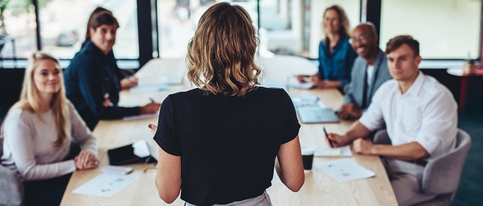 Rear view of a businesswoman addressing a meeting in office. Female manager having a meeting with her team in office boardroom.