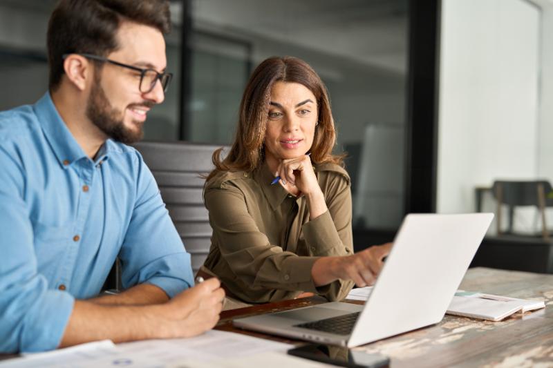 Business man and woman working together with laptop and papers
